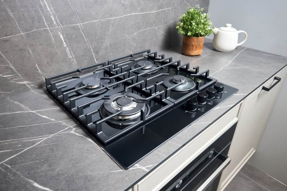 Gas stove with modern kitchen countertop and decorative plant, plumbing and heating services.
