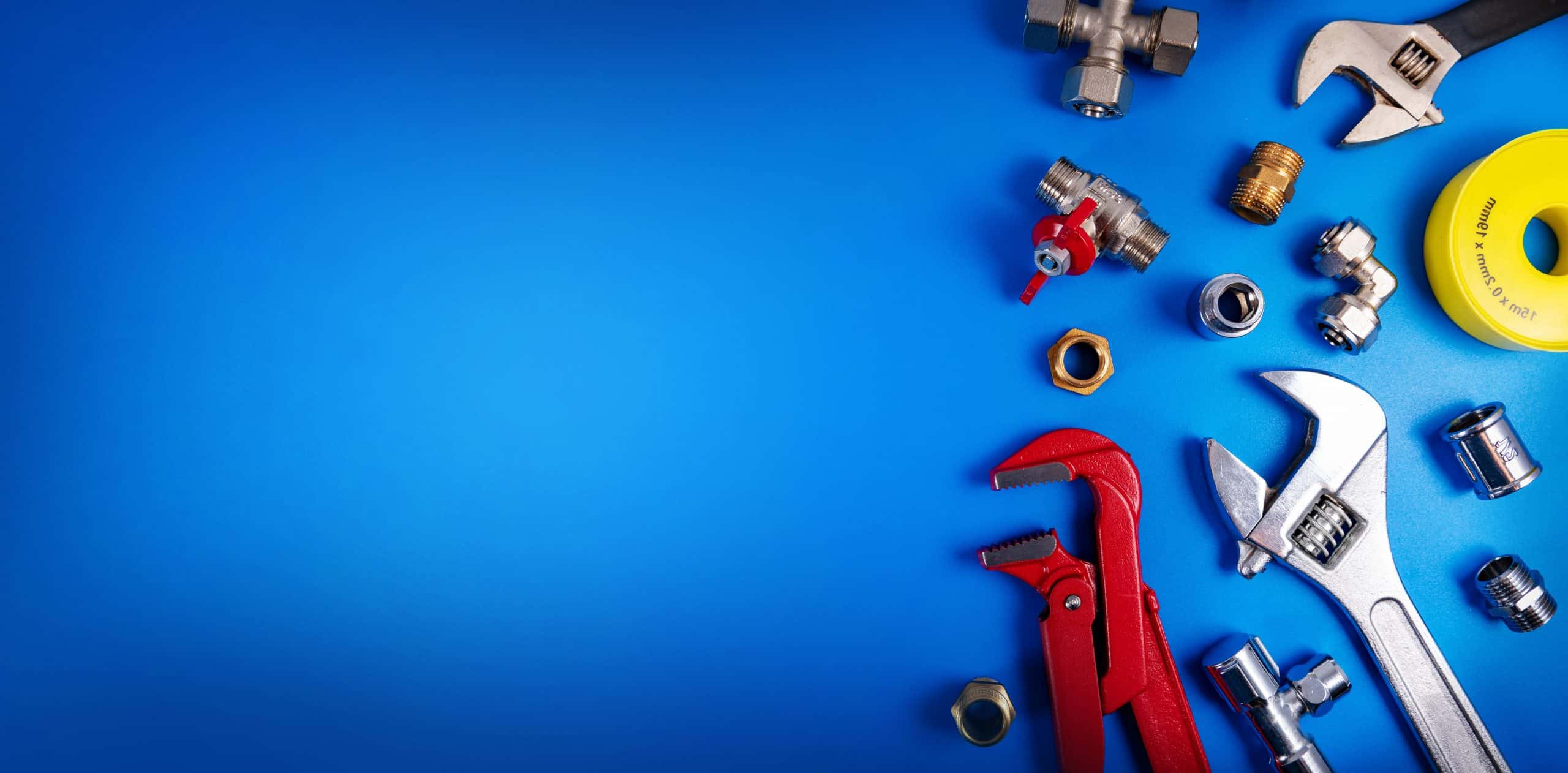 Plumbing tools and fittings, perfect for any Plumbing Company New York County & Staten Island, NY, including wrenches, pipe connectors, and yellow sealing tape, are arranged on the right side of a bright blue background.