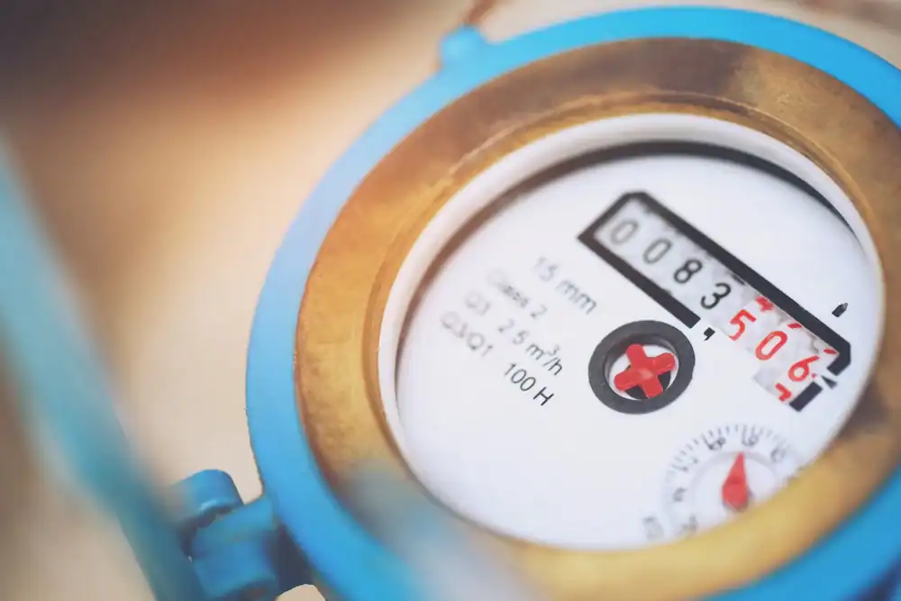 Close-up of a blue-rimmed water meter displaying numerical readings and measurement units, with the meter&rsquo;s dial and indicator clearly visible.